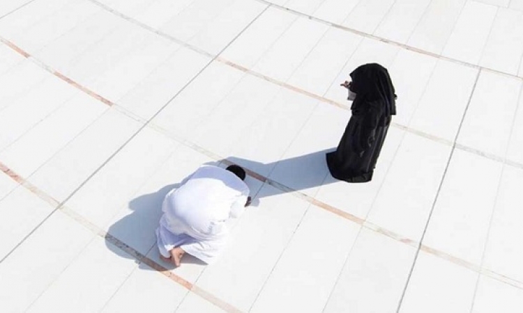 سعودى يصلى فى ظل زوجته بساحة الحرم المكى للوقاية من الشمس